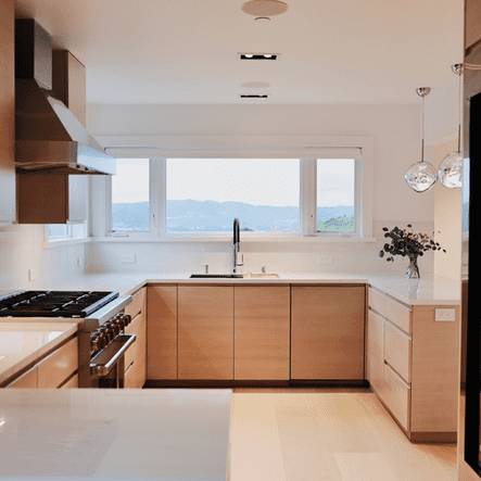 A modern kitchen with white cabinets, quartz countertops, and stainless steel appliances, remodeled by a professional kitchen remodeling company in San Ramon, CA.